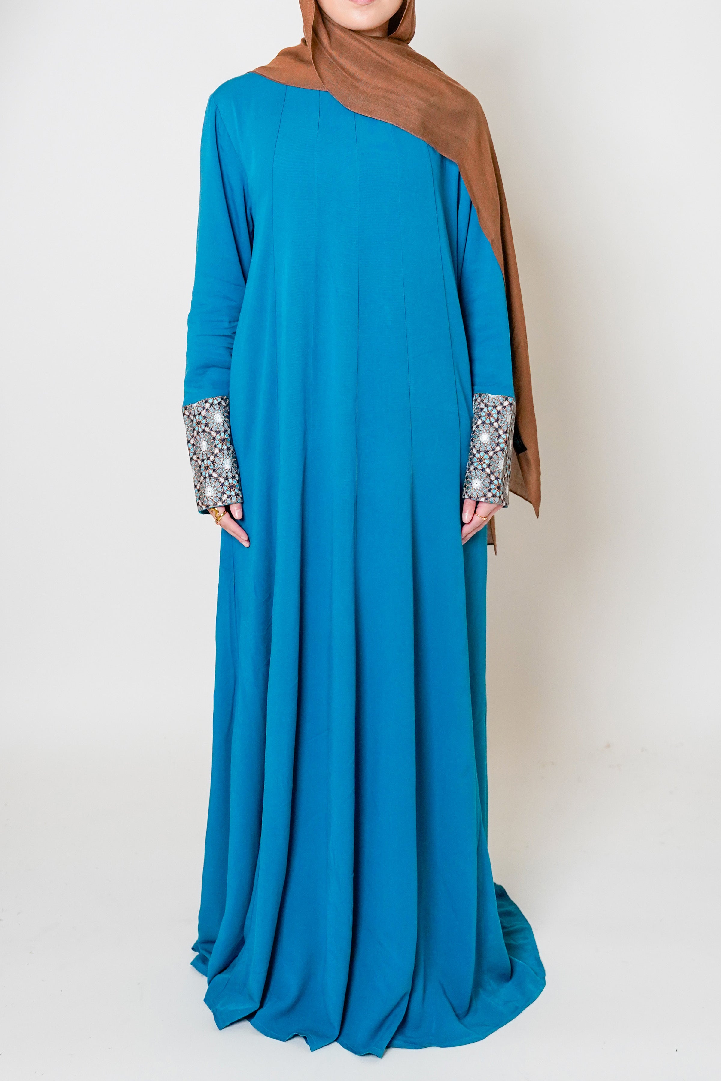 Luxury Caspian Blue Embroidered Cuff Abaya – Indulge in the opulent elegance of our Luxury Caspian Blue Abaya, featuring intricate embroidery on the cuffs that adds sophistication. Crafted in a soft fabric with panels for a rich and full flow, offering ultimate comfort.