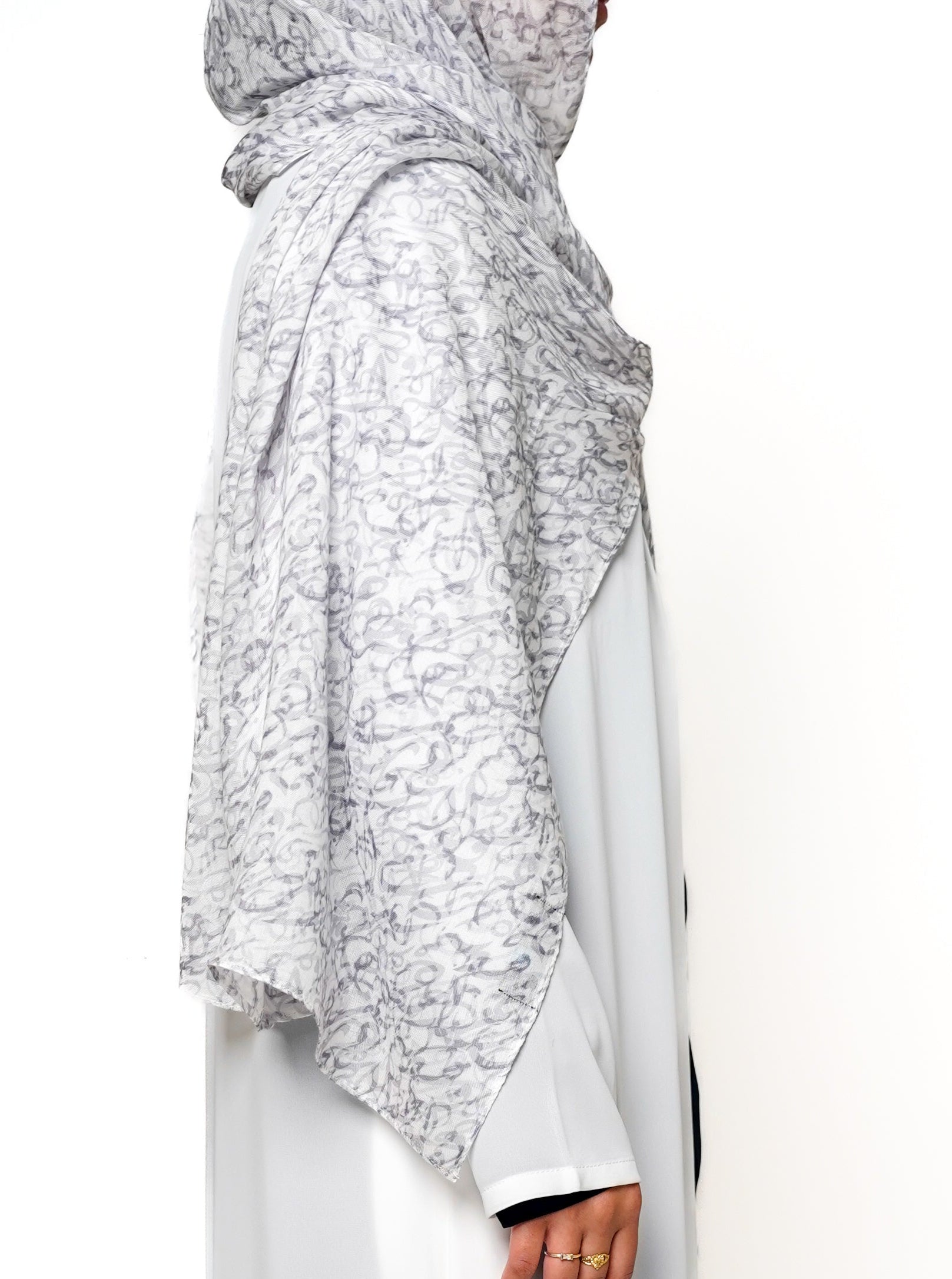 Sacred Script Bamboo Modal Hijab in a soft white color featuring a delicate abstract pattern in shades of gray, offering a subtle and elegant design.