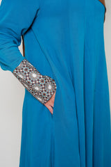 Side view of the Luxury Caspian Blue Embroidered Cuff Abaya, highlighting the intricate cuff embroidery in blue and gold with side pockets. The abaya is made from soft fabric with a flowing design, offering both sophistication and comfort.