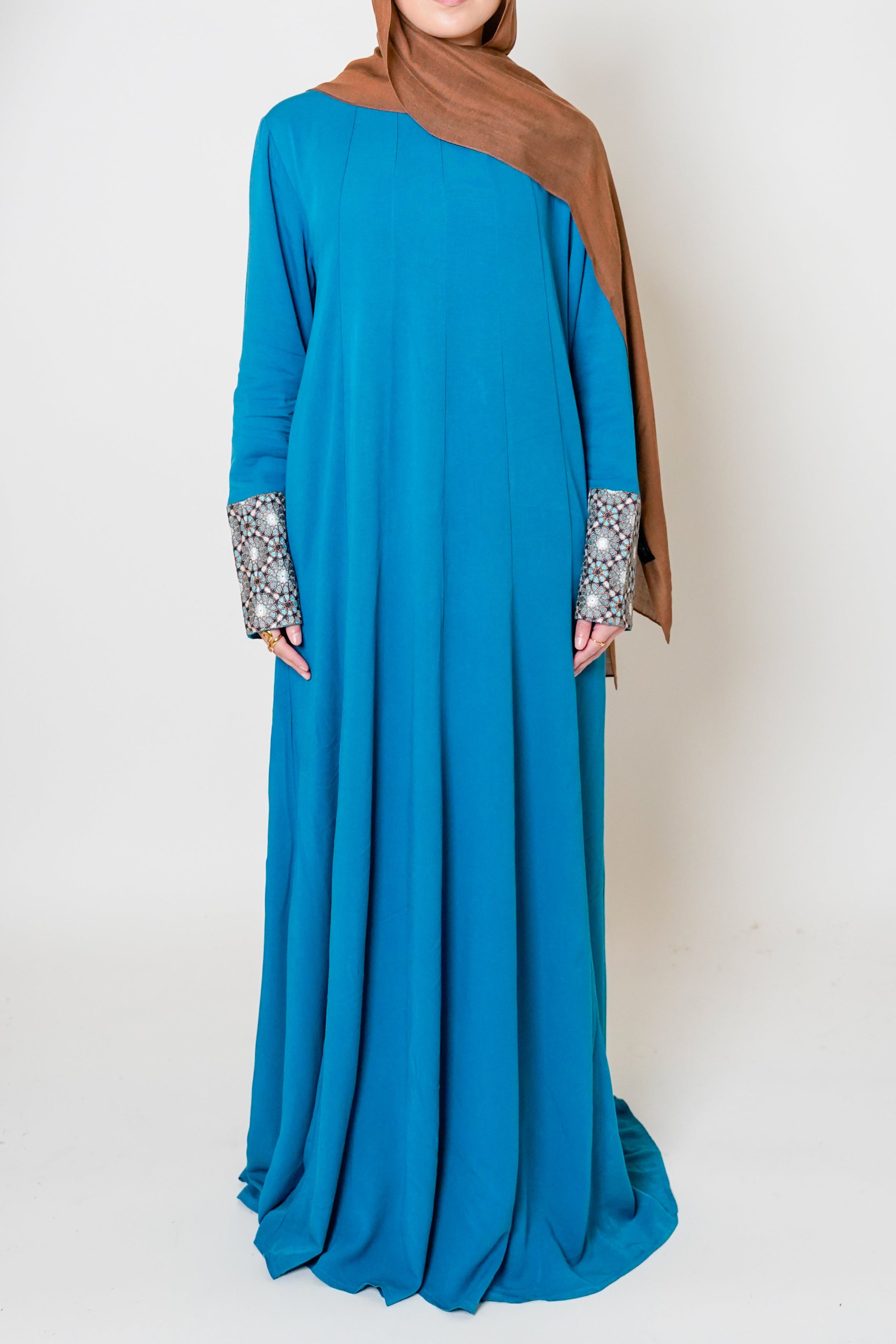 Full view of the Luxury Caspian Blue Embroidered Cuff Abaya, with intricate embroidery on the cuffs in blue and gold. The abaya is made from soft fabric with flowing panels, providing both sophistication and ultimate comfort