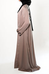 A woman wearing a stone embroidered kimono with black floral embroidery on the upper back, paired with a black hijab