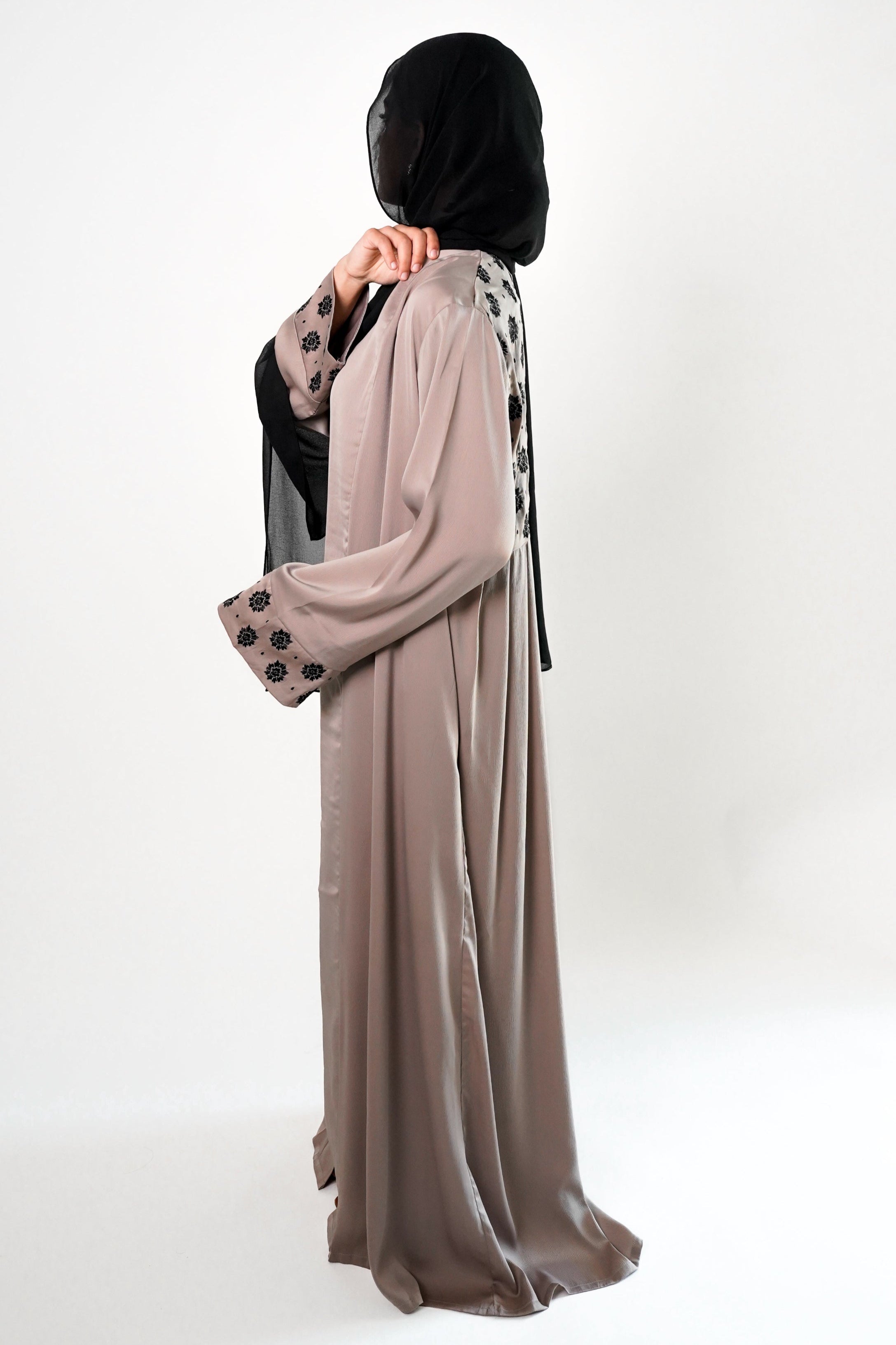 A woman wearing a stone embroidered black kimono with black floral embroidery on the upper back, paired with a black hijab